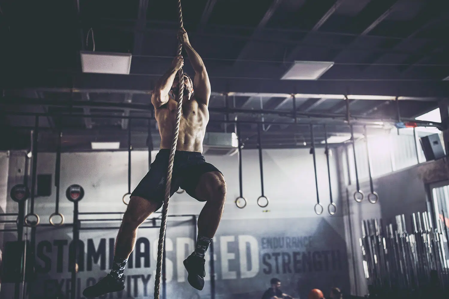 Fitness funzionale arrampicata su corda con uomo muscoloso